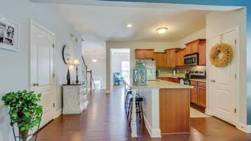 A modern kitchen with wooden cabinets, a central island, and a dining area with bar stools.
