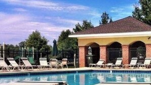 Un área de piscina con sillas de descanso y un pabellón cubierto.