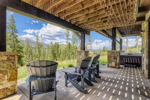 Una terrazza esterna con pareti in pietra, una pergola in legno e vista su un paesaggio montuoso.