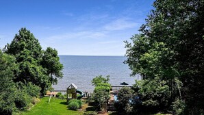 A view of a grassy area with a playground and a small wooden structure, overlooking a body of water.