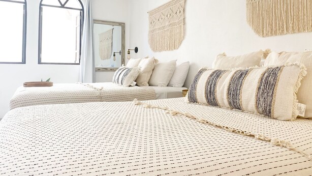 Un dormitorio con una cama grande, un tapiz de macramé y un espejo.
