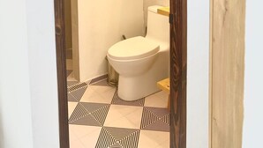 Un baño con inodoro, ducha y lámpara colgante.