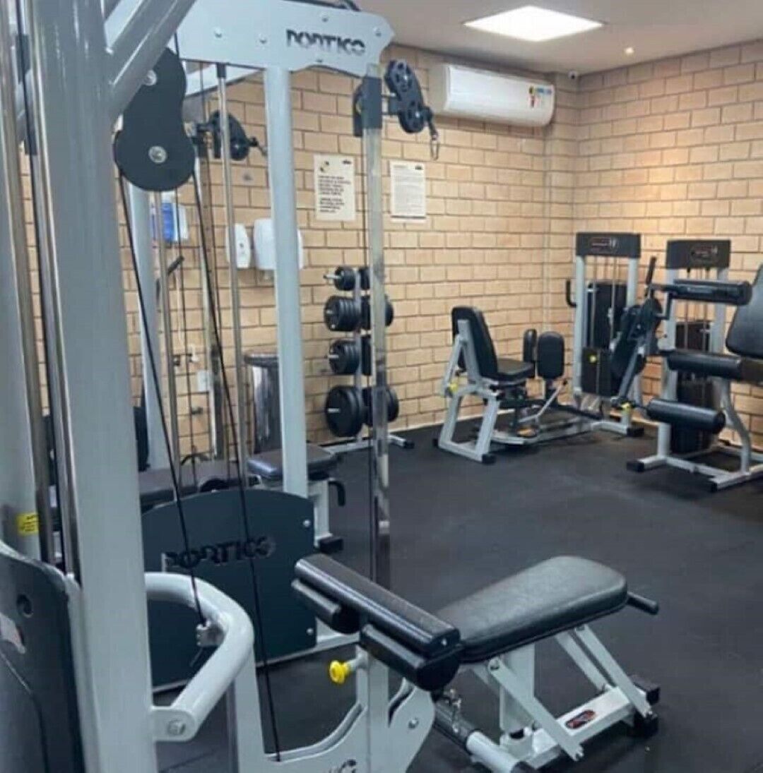 A gym with weightlifting equipment, a bench, and a brick wall.