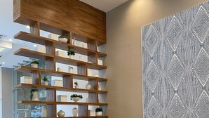 Un salon moderne avec un canapé d’angle, des étagères en bois et un mur orné d’un motif géométrique.