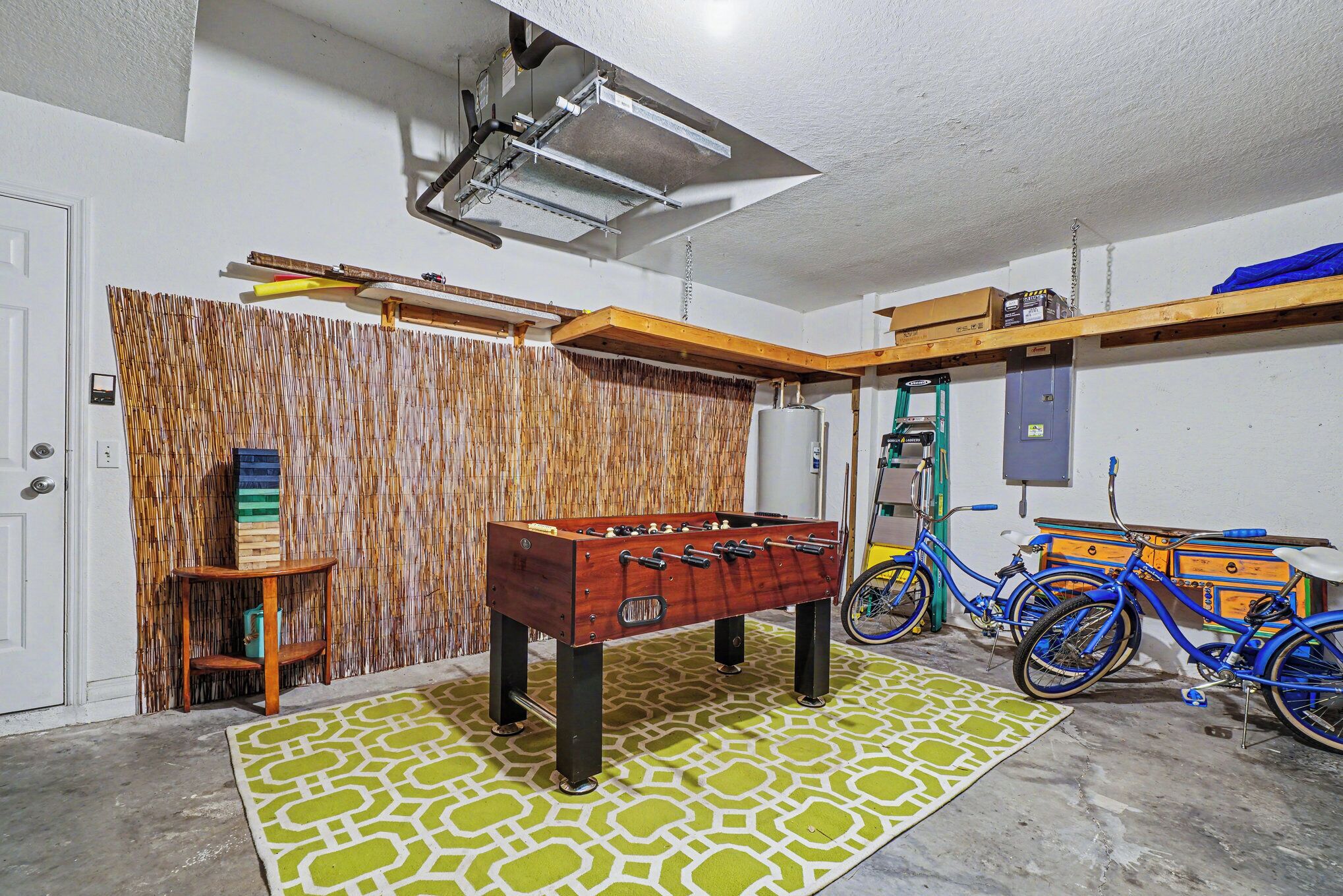A room with a foosball table, bicycles, and a patterned rug.