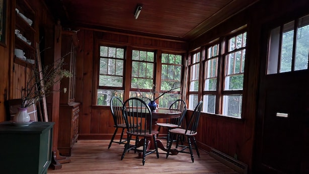 Un interior de madera con una mesa y sillas de comedor, ventanas amplias y un armario verde.
