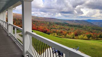 A covered porch with a view of a colorful autumn landscape.