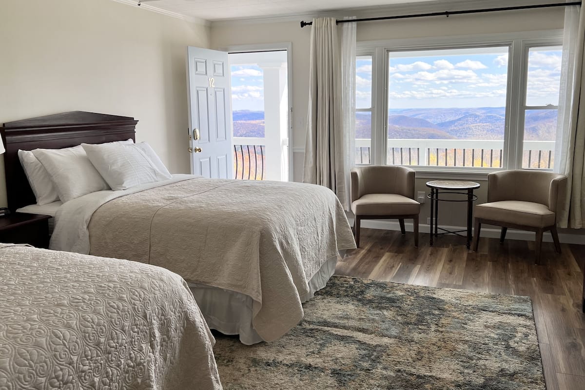 A hotel room with two beds, a small table, and chairs.