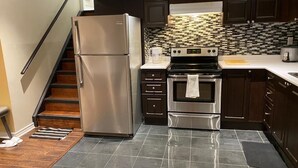 A modern kitchen with stainless steel appliances, a tiled backsplash, and dark cabinetry. - Bright and Clean Basement Apartment,5 min to Lakes. (Richmond Hill)