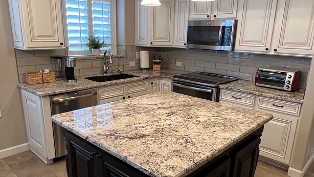 A kitchen with white cabinets, a granite island, stainless steel appliances, and pendant lighting. - Desert Ridge * Location Location Location  (Phoenix)