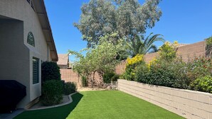 A well-maintained backyard with artificial grass, a brick wall, and various plants and trees. - Desert Ridge * Location Location Location  (Phoenix)
