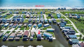 Eine Luftaufnahme eines Wohngebiets mit Häusern und einem Wasserweg, im Hintergrund das Schild "BEACH".