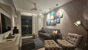 Un saló modern amb un sofà, un reposapius, una làmpada de peu i obra d'art a la paret.