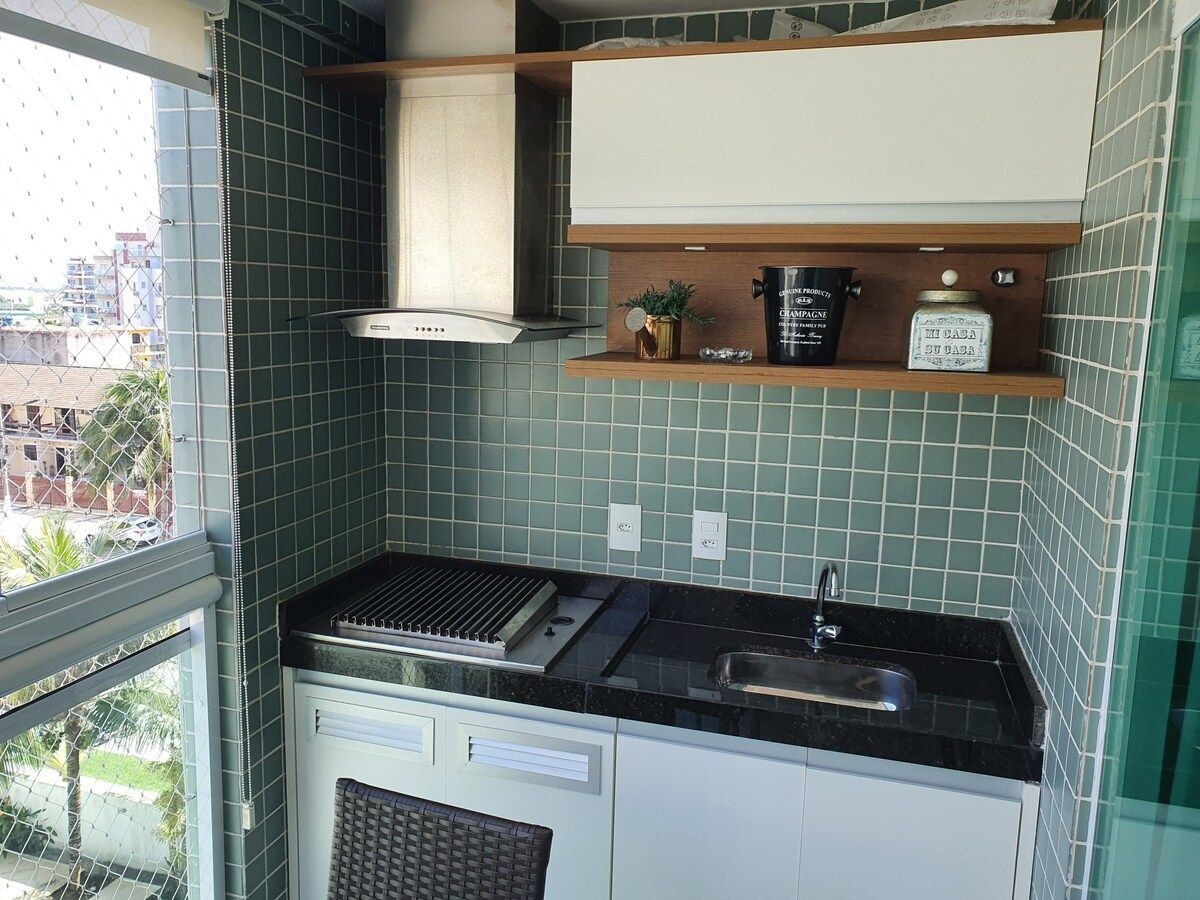 A compact kitchen with a gas stove, a sink, and a built-in oven. There is a window with a view of buildings outside.