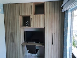 Una habitación con escritorio integrado, una silla y un televisor.