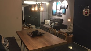 A modern living room with a dining area, a sofa, and a TV. - Lindo AP completo no Braga em Cabo Frio (Cabo Frio)