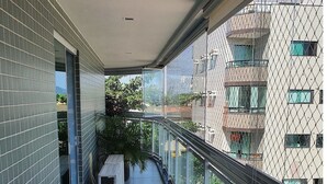 A balcony with a metal railing, a row of chairs, and potted plants. - Lindo AP completo no Braga em Cabo Frio (Cabo Frio)
