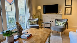 A living room with a large window, a television, a cabinet, and a coffee table. - Walcot Yard in Bath (Bath)
