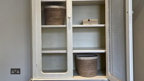 A white, ornate armoire with a hinged door, multiple shelves, and a mesh window. - Walcot Yard in Bath (Bath)