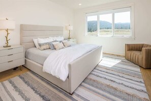A bedroom with a large bed, bedside tables, a window with a view, and a chair. - Opulent 4 Bedroom Townhouse (Big Sky)