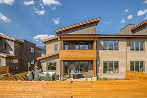 A modern multi-story residential building with a wooden facade, large windows, and a well-maintained garden area. - Opulent 4 Bedroom Townhouse (Big Sky)