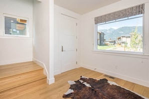 Una habitación con un ventanal grande, suelo de madera y alfombra de cuero.