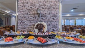 Un bufé con diversos alimentos y una pared de piedra con una decoración de cabeza al fondo.