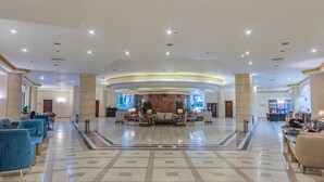 Un vestíbulo amplio con una zona de estar central, un mostrador de recepción y un diseño de techo moderno.