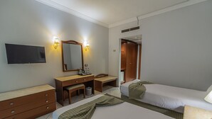 Una habitación de hotel con dos camas, un escritorio, un espejo, un televisor y un armario.