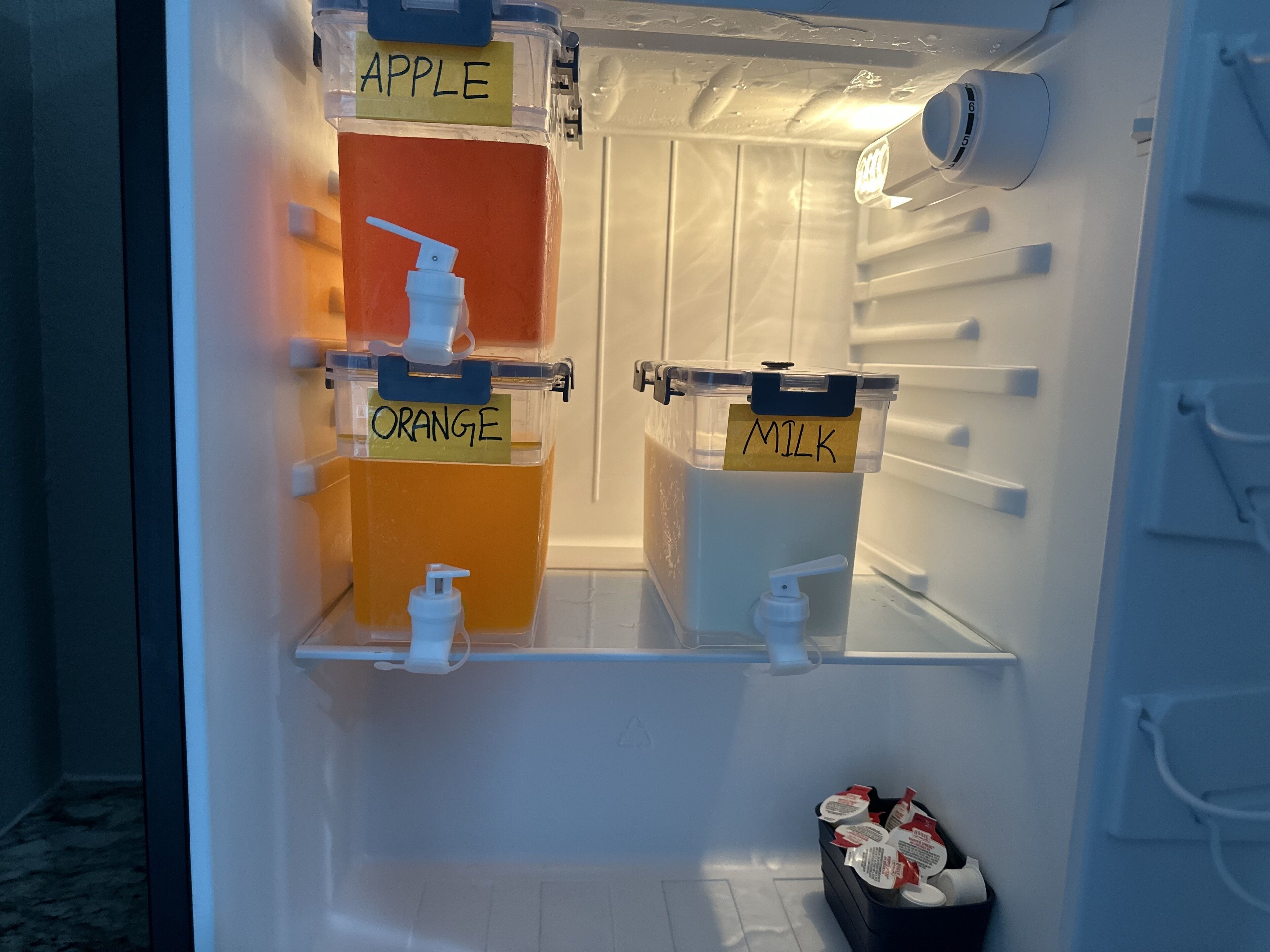 A refrigerator with labeled compartments for apple juice, orange juice, and milk.