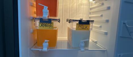A refrigerator with labeled compartments for apple juice, orange juice, and milk.