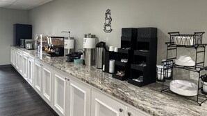A modern kitchen with a marble countertop, built-in cabinets, and a coffee station with dispensers and cups. - Crystal Inn (Port Arthur)