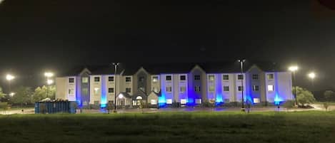 Un edificio de varios pisos con techo plano, iluminado por luces azules.
