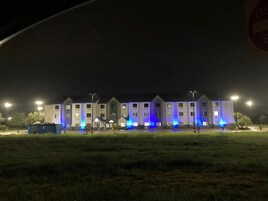 Un edificio de varios pisos con techo plano, iluminado por luces azules.