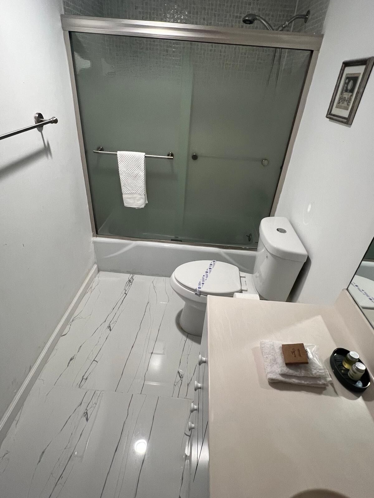 Een moderne badkamer met een douchecabine van glas, een toilet en een wastafel met toiletartikelen.
