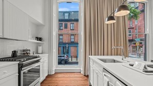Eine moderne Küche mit einem großen Fenster, Holzboden und Blick auf die Straße.