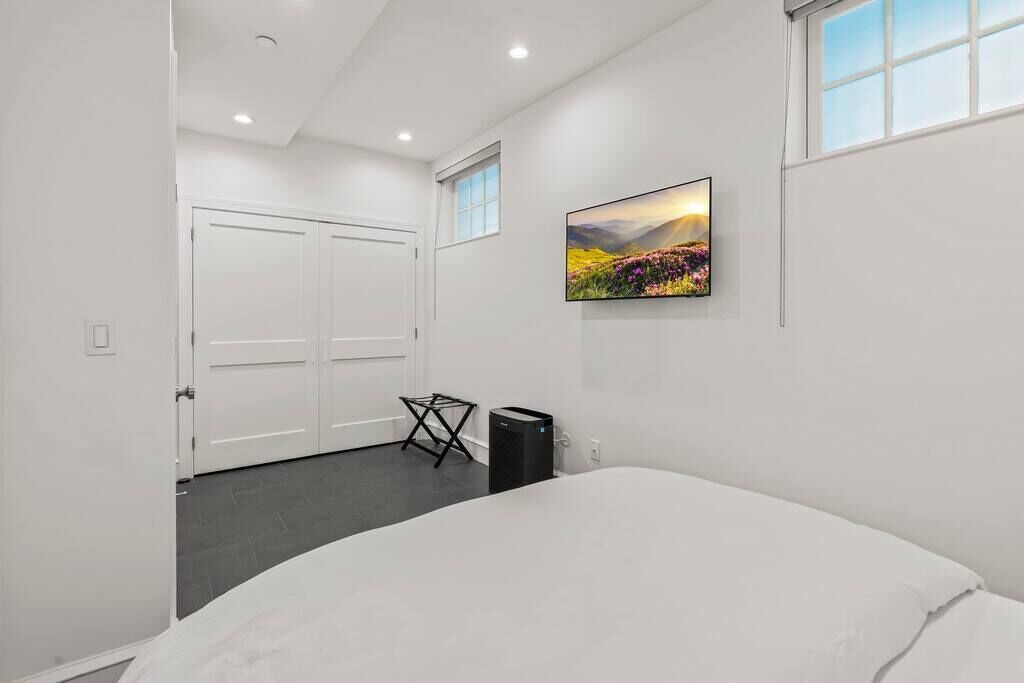 Um quarto com uma cama grande, um quadro na parede, uma janela e uma porta.