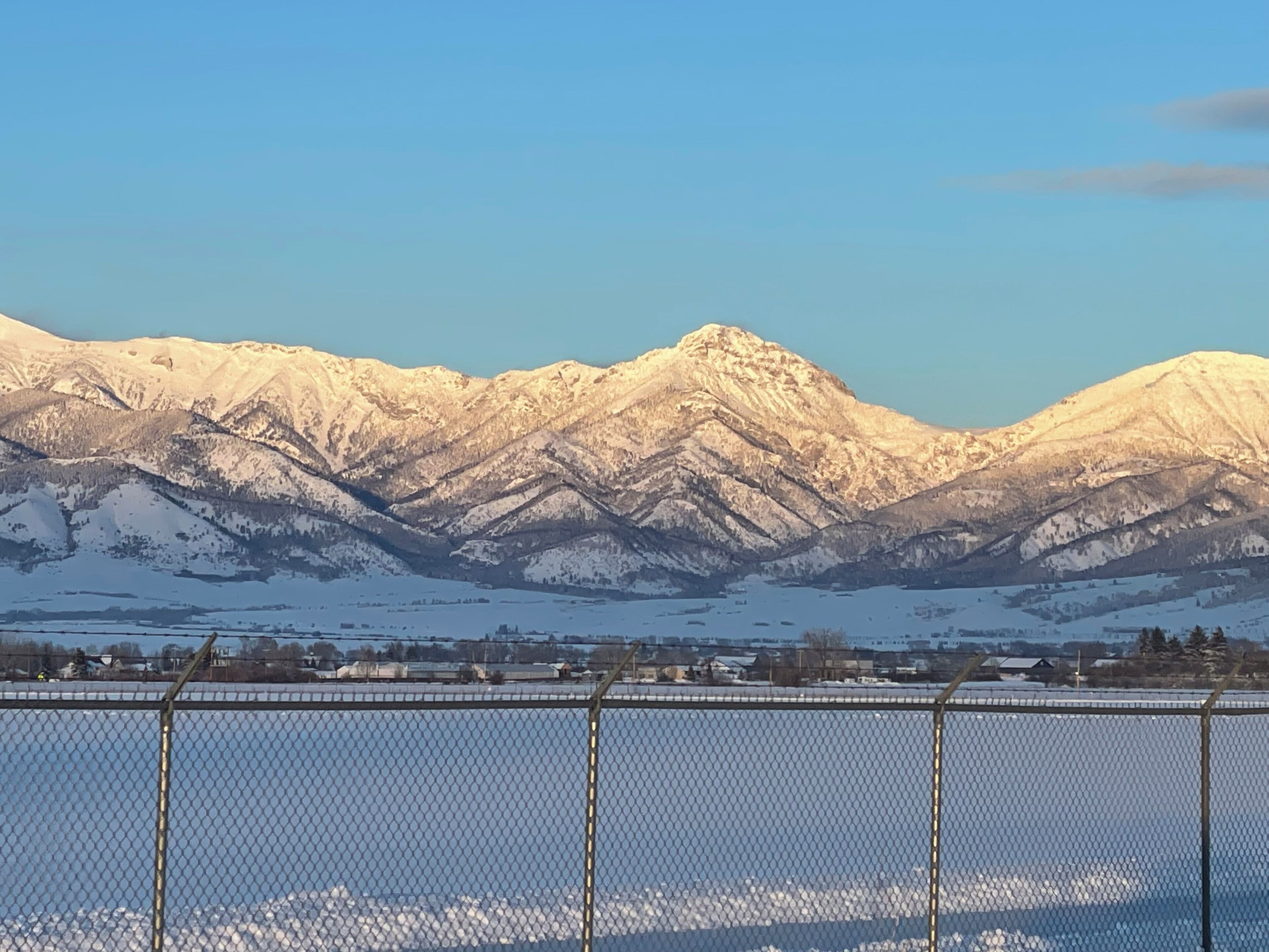 A mountainous landscape with snow-covered peaks and a clear sky.