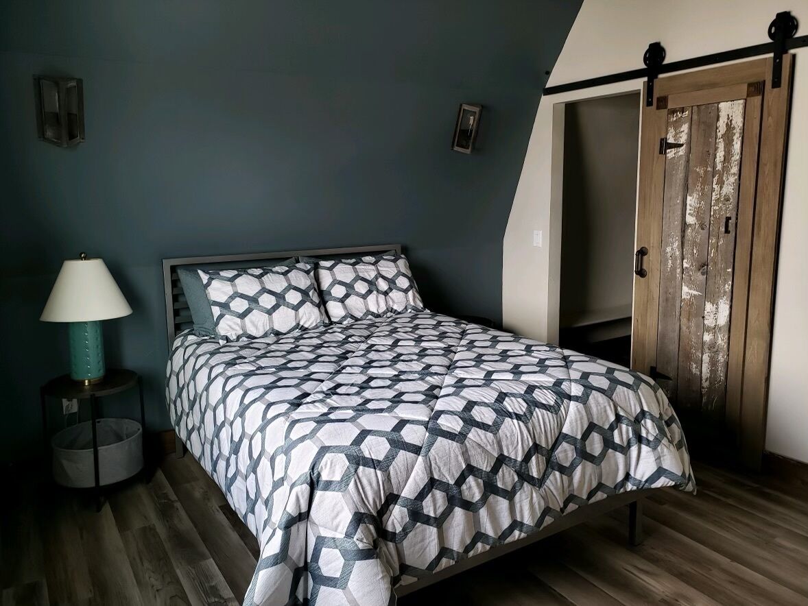 A bedroom with a bed, a nightstand, a lamp, and a sliding door.