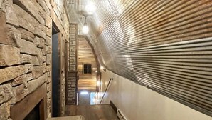 Un couloir étroit aux murs de pierre et au plancher en bois, qui mène à un escalier.