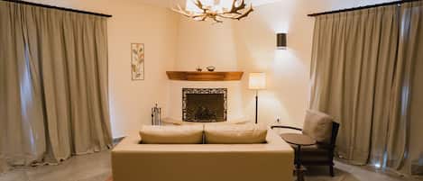 Una sala de estar moderna con un sofá grande, una chimenea, un candelabro y cortinas.