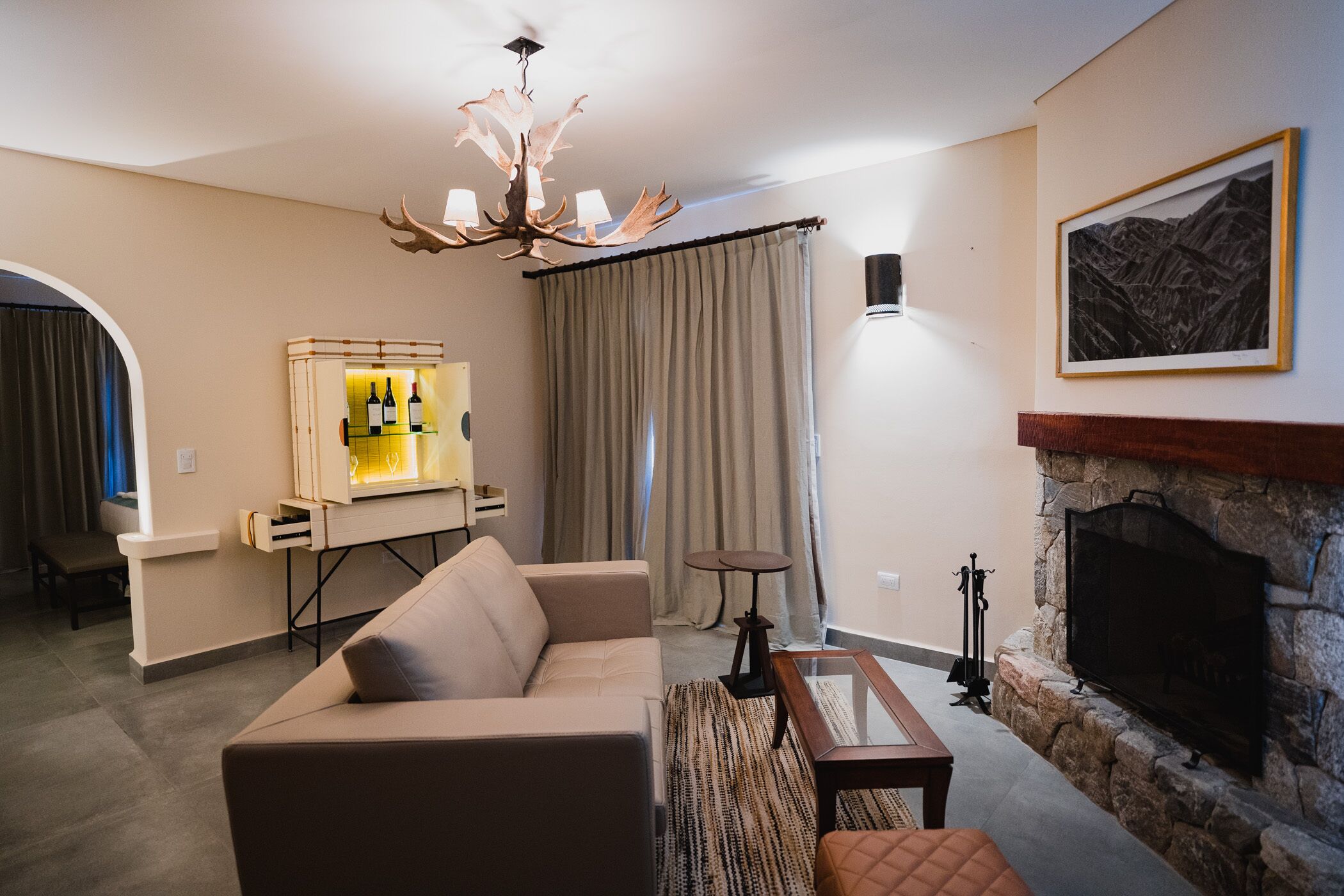 Una sala de estar con sofá, mesa de centro, chimenea, televisor y una vitrina para vino.