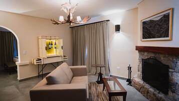 Una sala de estar con sofá, mesa de centro, chimenea, televisor y una vitrina para vino.
