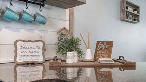 A kitchen counter with a welcome sign, salt and pepper shakers, a small potted plant, and a sign that says 'love grows best in little houses just like this.'