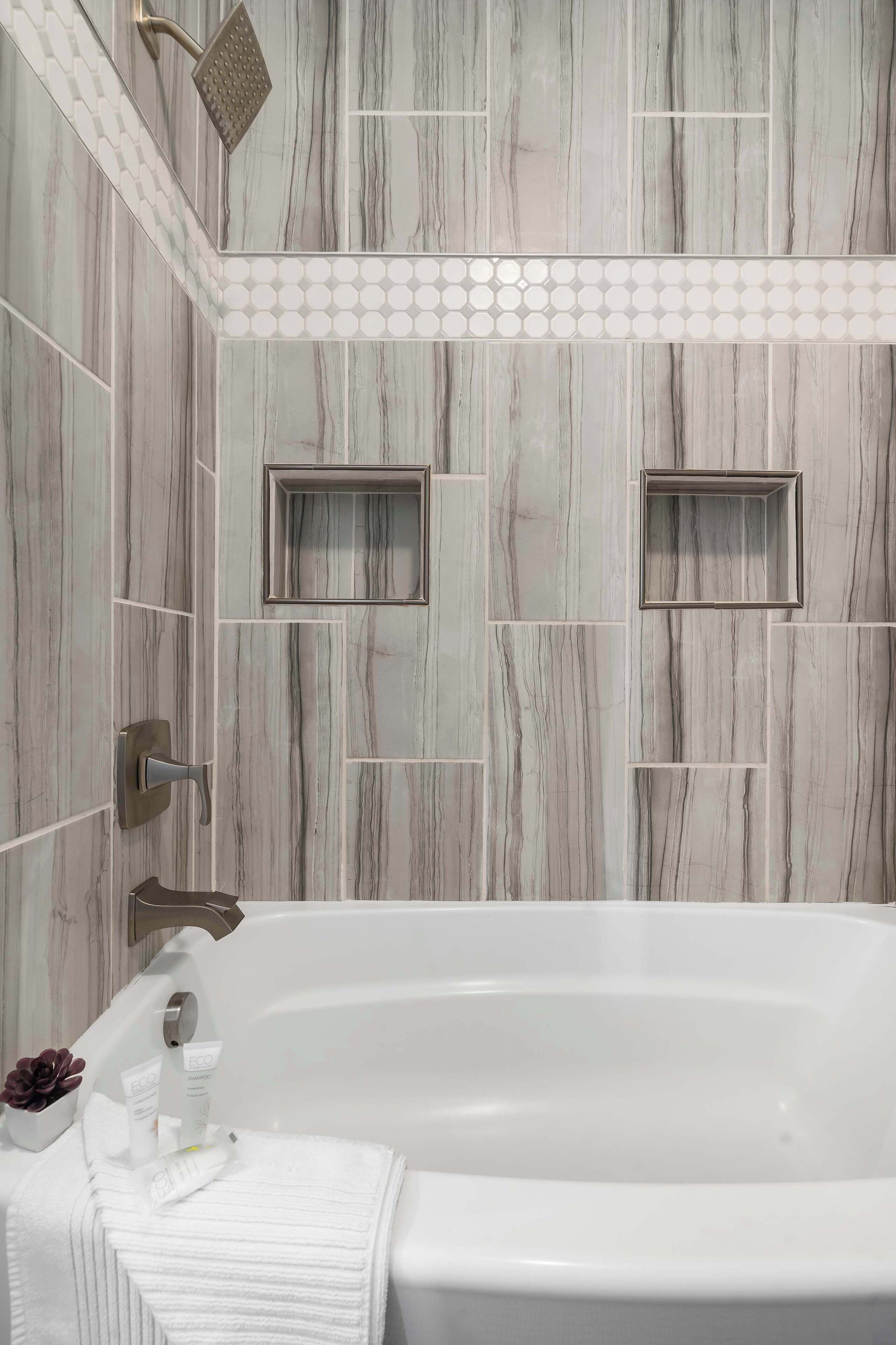 Une salle de bain avec une baignoire, une douche et des murs carrelés.