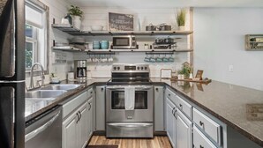 A modern kitchen with stainless steel appliances, wooden countertops, and a farmhouse aesthetic.