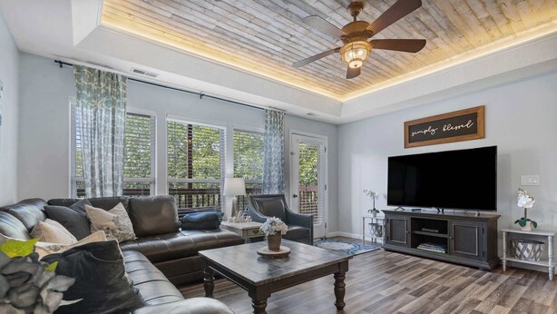 A living room with a sectional sofa, a coffee table, a TV, and a ceiling fan.