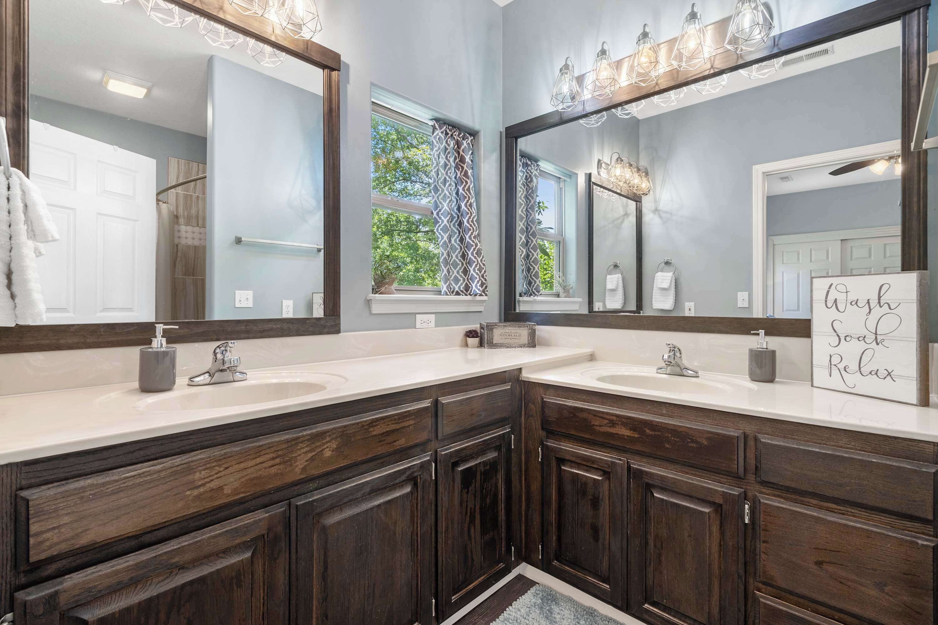 A modern bathroom with two sinks, dark wood cabinets, and large mirrors.