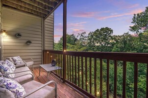 A covered porch with outdoor furniture, a small table, and string lights.