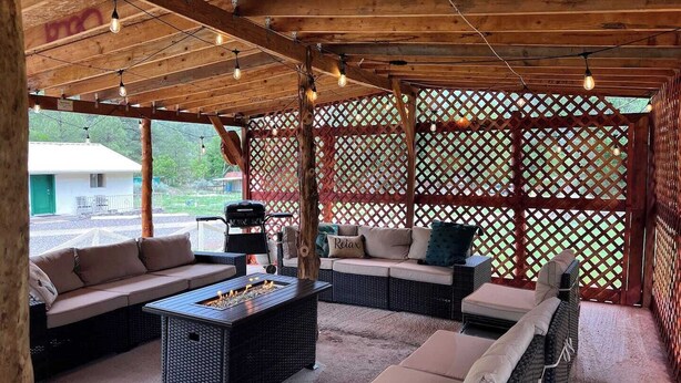 An outdoor patio with wicker furniture, a fire pit, and string lights. - Cozy cabin at Inn at Lake Roberts (Lake Roberts)